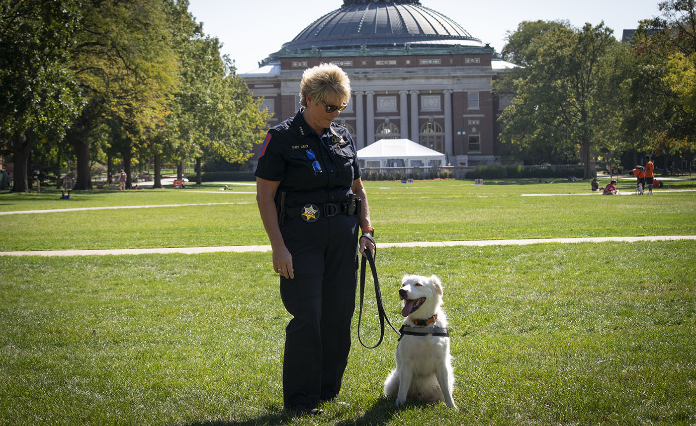 Chief Cary and K-9 Archie pose for a photo on the quad with Foellinger Auditorium in the background.