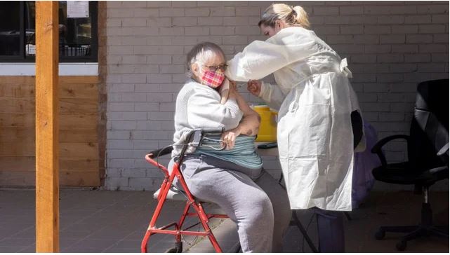older woman with walker gets a Covid shot. Image from Getty Images