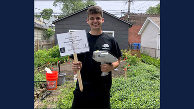Graduate student George Watson, first author on the study, holds a sign and a soil analyzer in a Chicago backyard.