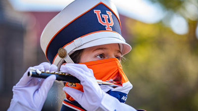A piccolo player performs with the Marching Illini  wearing special masks designed with an opening that accommodates an instrument mouthpiece.