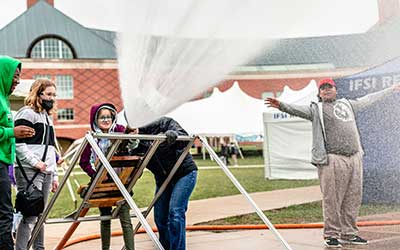a elementary student tries her hand at operating a firehose at Engineering Open House