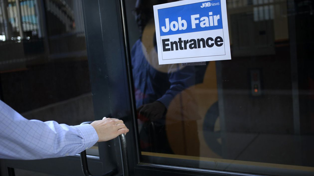 hand opens door to a job fair. Photo by Luke Sharrett for Bloomberg News