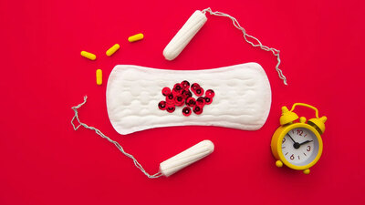 stock image of feminine pad, tampons, capsules and an alarm clock by DEPOSIT PHOTOS