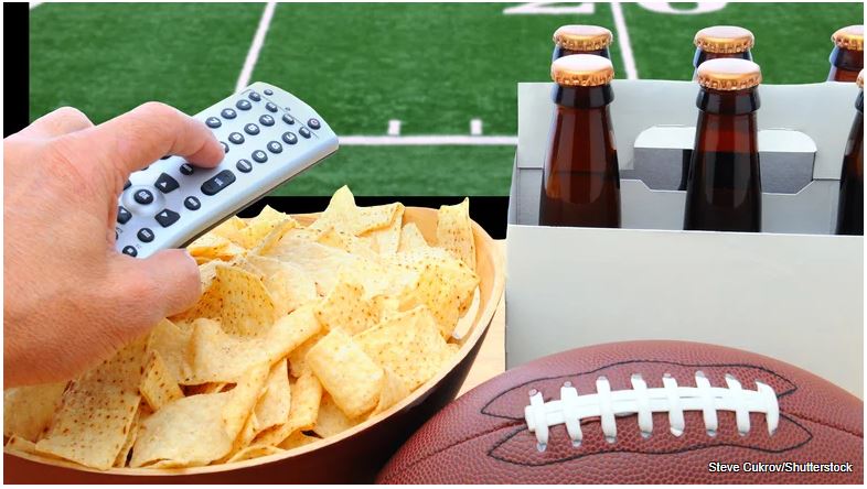 stock image shows football, TV remote, bowl of chips and beer. Photo by Steve Oukrov via Shutterstock