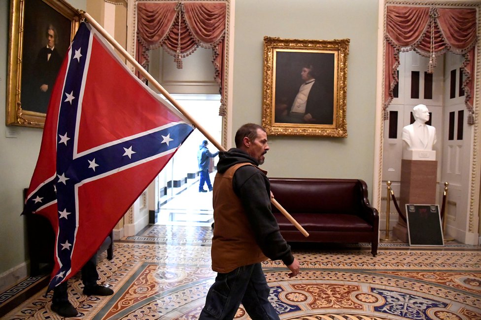 Man carries a Confederate battle flag inside the United States capitol. Photo by Mike Theiler / Reuters