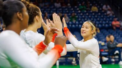 an Illini volleyball player high-fives other Illini volleyball players