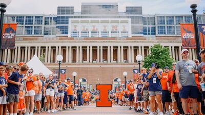 tailgating fans line the path where Illini Football players will enter the stadium