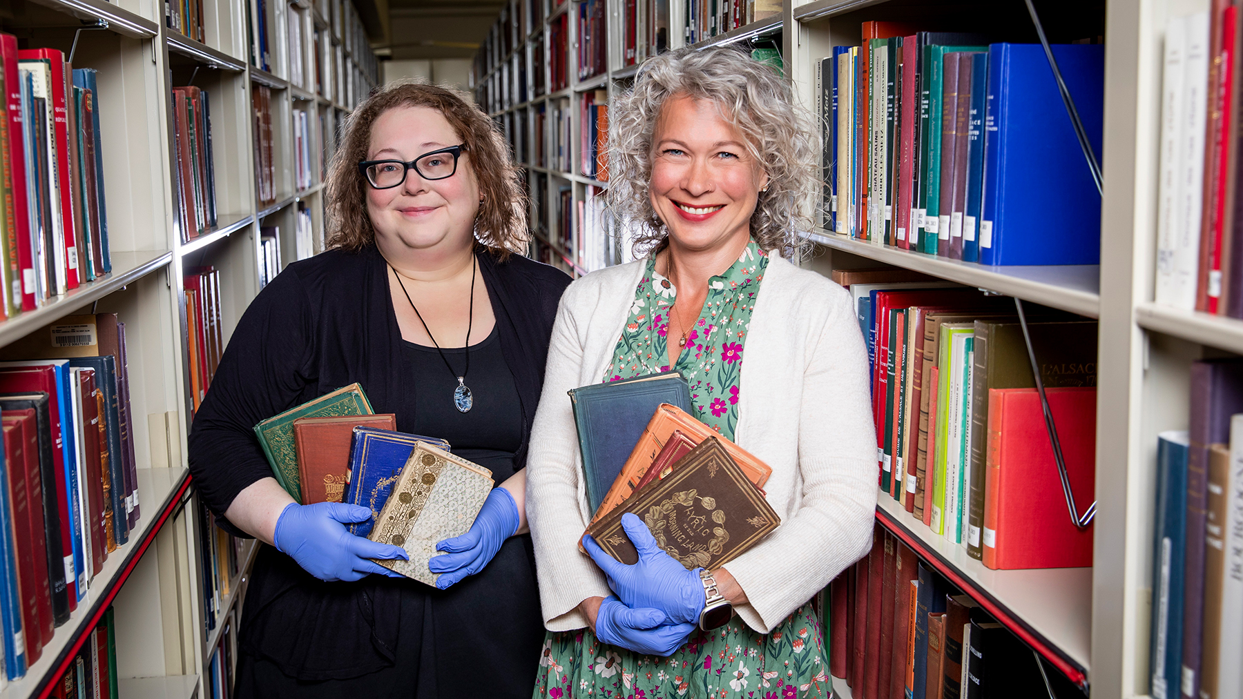 Shelby Strommer, the collections care coordinator for Preservation Services, and Jennifer Hain Teper, the head of Preservation Services for the University Library, hold Victorian-era books. Photo by Michelle Hassel
