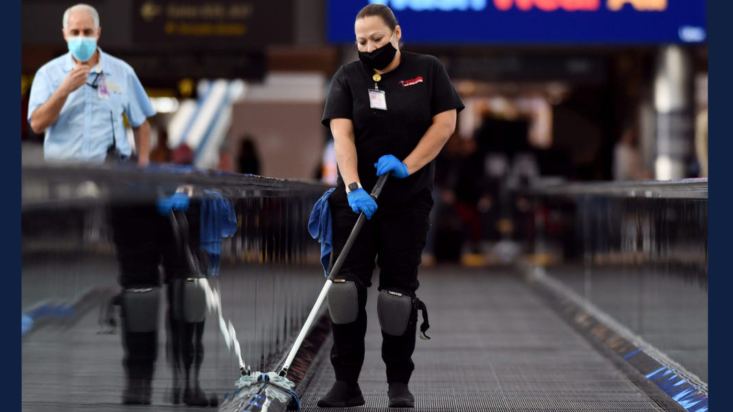 woman cleans the moving sidewalk at an airport. Hyoung Chang/MediaNews Group/The Denver Post via Getty Images