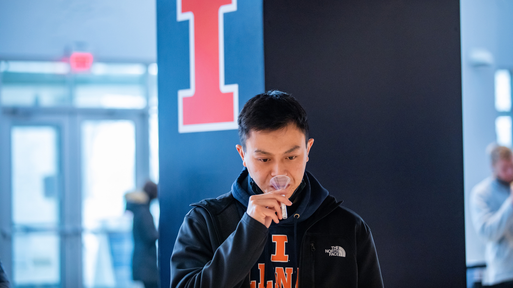 Illinois student uses a funnel to spit in a tube as part of COVID testing