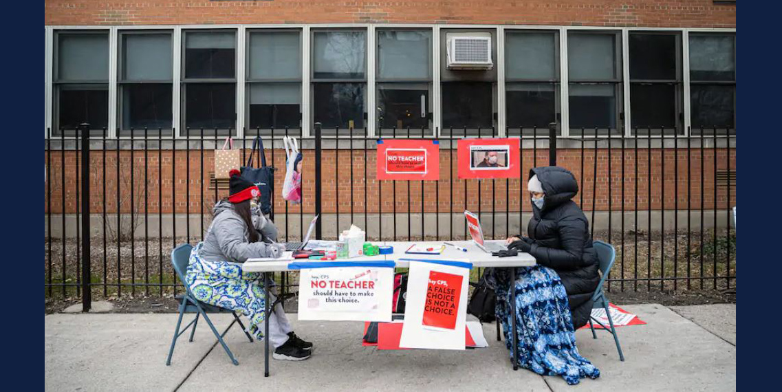 Teachers Adrienne Thomas and Irene Barrera set up outside Suder Montessori Magnet Elementary School in Chicago on Jan. 11 in solidarity with pre-K educators who had to return to work in the building. (Anthony Vazquez/Chicago Sun-Times/AP)