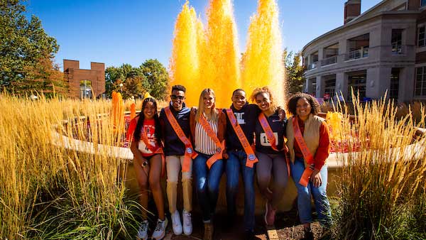 2022 Homecoming Court members sit beside the fountain near Alice Campbell Alumni Center. The fountain has been dyed orange for Homecoming. Photo by Michelle Hassel