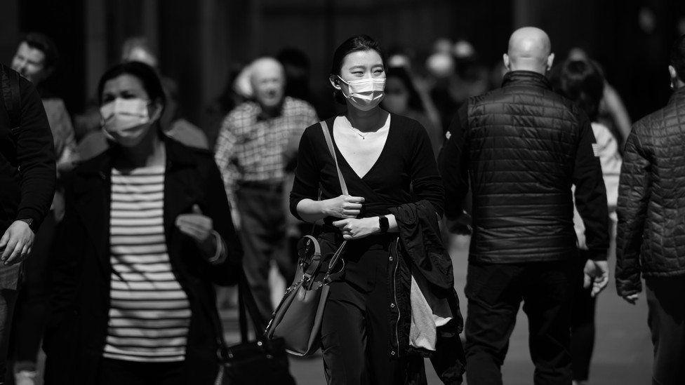 masked people walking along a street. Photo by Noam Galai / Getty