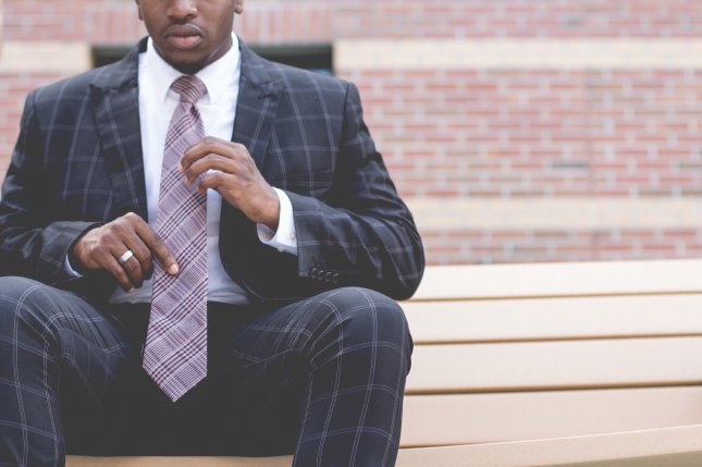 African American man in suit adjusts his tie. Stock image from StockSnap/Pixabay