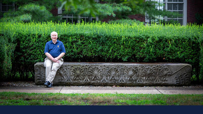Dennis Craig sits at the ornately carved granite bench north of the Architecture Building.