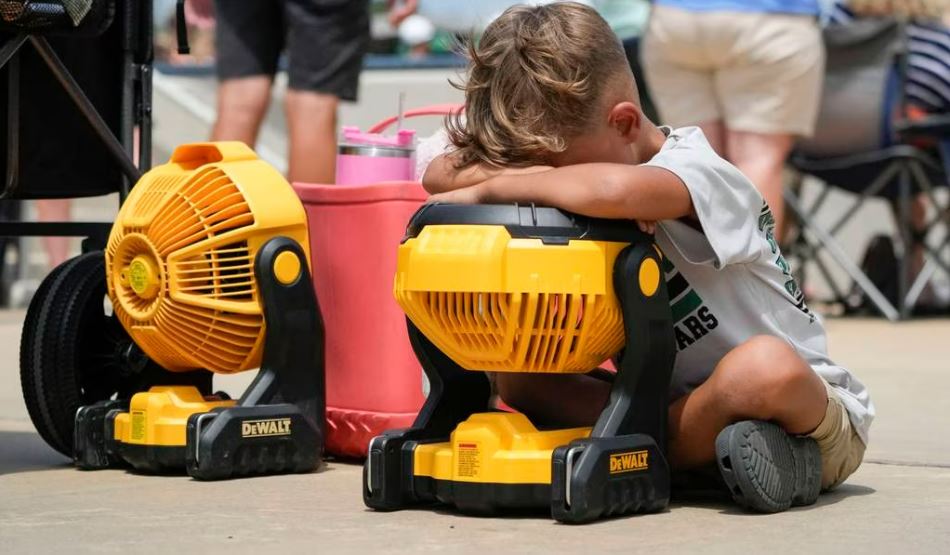 Braxton Hicks, 7, of Livingston, Texas, holds his face to a portable fan to cool off during a heat wave that occurred during a baseball tournament in Ruston, Louisiana, earlier this month. With climate change driving average global temperatures higher, teams and parents are having to pay closer attention to the heat. (Gerald Herbert/AP)