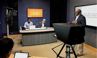 Professor lectures in a TV studio-type setting. Illinois Gies has five iMBA studios on campus.