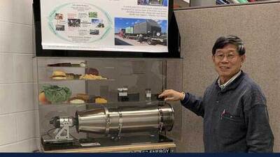 Yuanhui Zhang shows a poster and model of a USDA-funded project that aims to convert biowaste into fuels and pavement binder.
