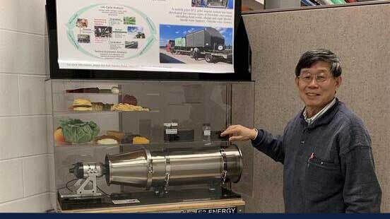 Yuanhui Zhang shows a poster and model of a USDA-funded project that aims to convert biowaste into fuels and pavement binder.