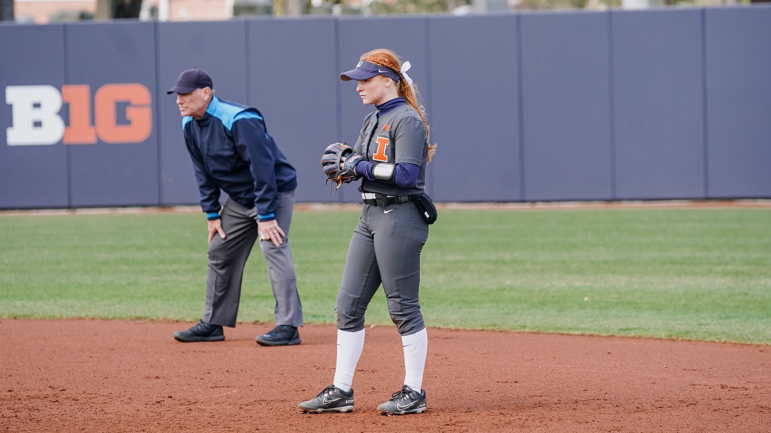 fifth-year infielder Avery Steiner stands near an umpire as she waits for a play to unfold