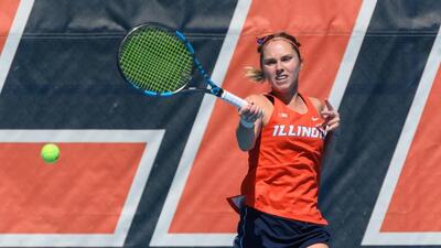 an Illini tennis player watches her return volley