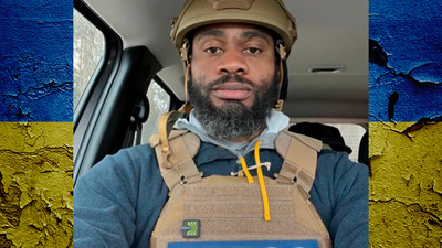 Terrell Jermaine Starr in flak jacket and helmet with the word 'press' in large print on the front of his jacket