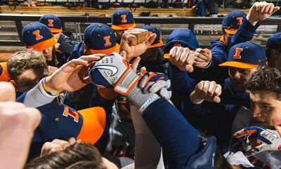 The Illini baseball team huddles with fists in the air after a win at Coastal Carolina ealier this year