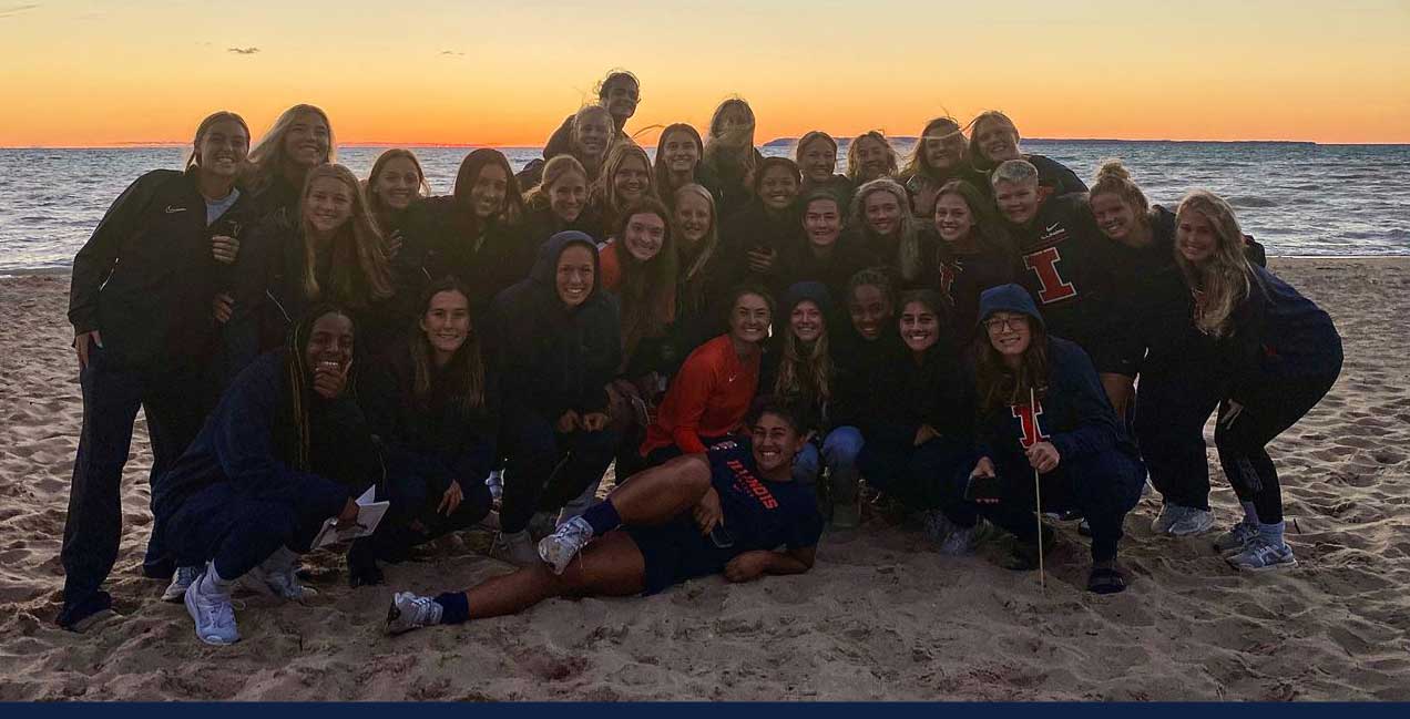 team photo on beach in Virginia with sunset