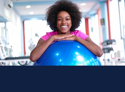stock image of woman looking very happy to be exercising with a large blue balance ball