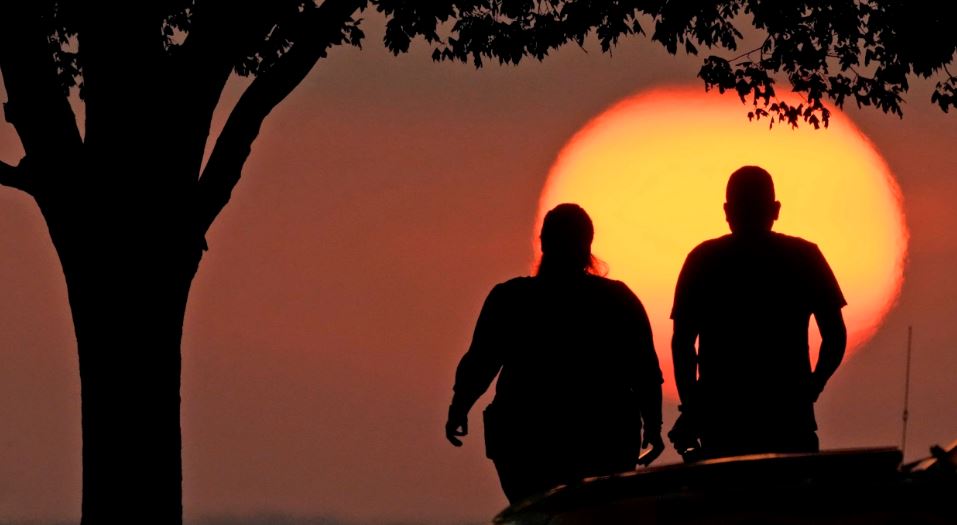 A couple watch the sunset Sunday in Kansas City, Mo., as triple-digit heat indexes continue in the Midwest. photo by Charlie Riedel / AP
