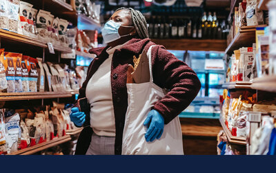 woman choosing food in grocery store wearing mask and latex gloves. Photo by Laura James