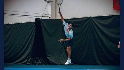 Illini tennis player leaps to hit an overhand shot