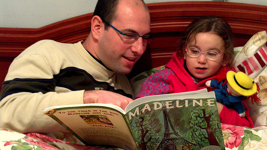 father reads book to young daughter. Photo via Creative Commons