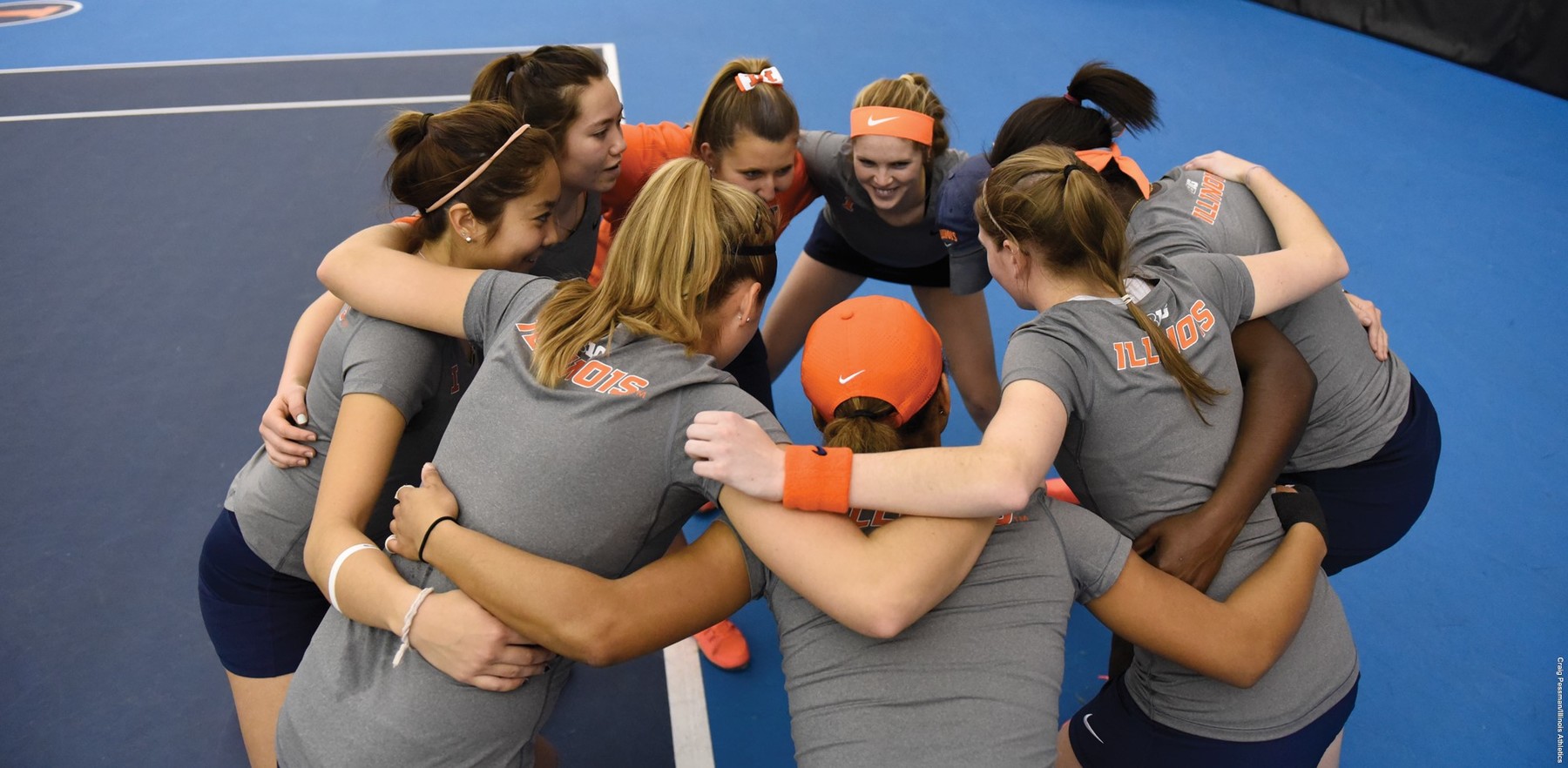 image of Illini tennis players huddling and smiling