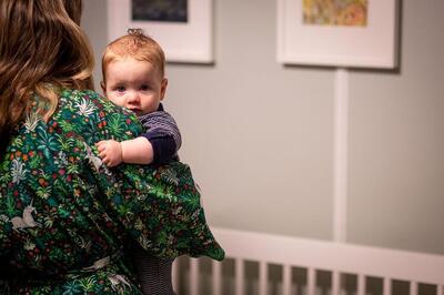 stock photo of a mother holding a baby beside a crib
