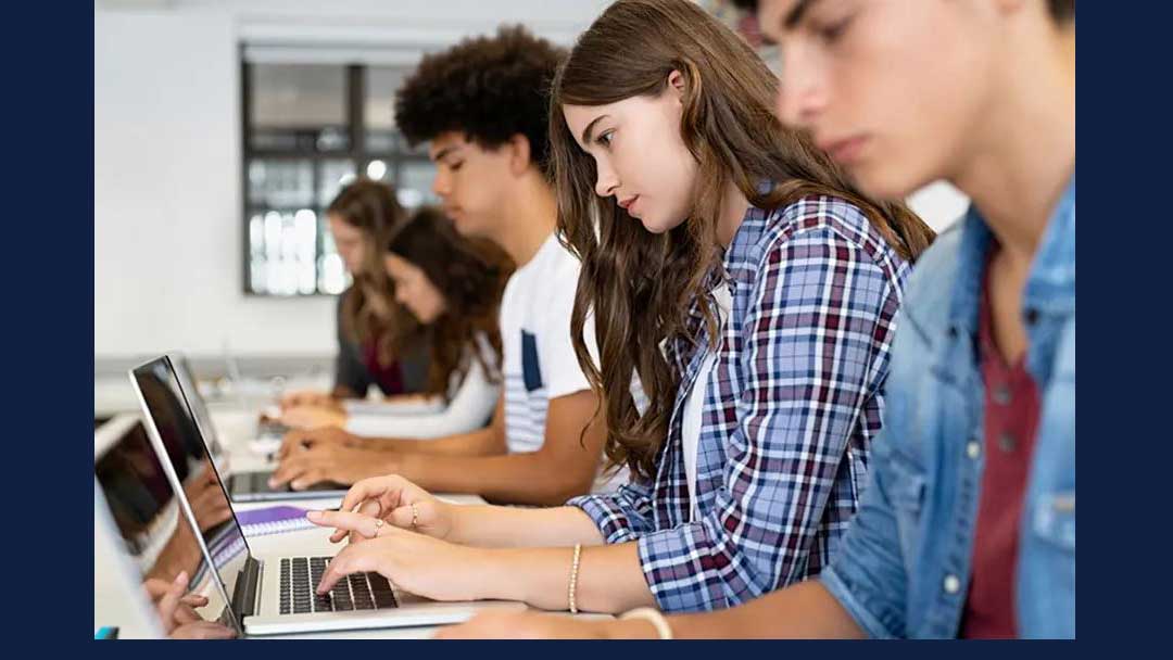 stock image of students working on laptops