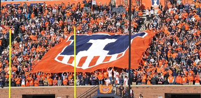 crowd at Memorial Stadium holding a huge 'Illini shield' banner