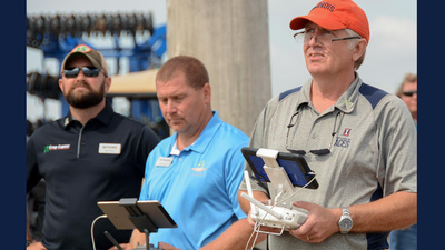 Ag technology educator Dennis Bowman (right) flies a drone