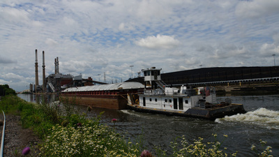 A tugboat pushes a barge on the Chicago Sanitary and Ship Canal past a coal-fired electric power plant.