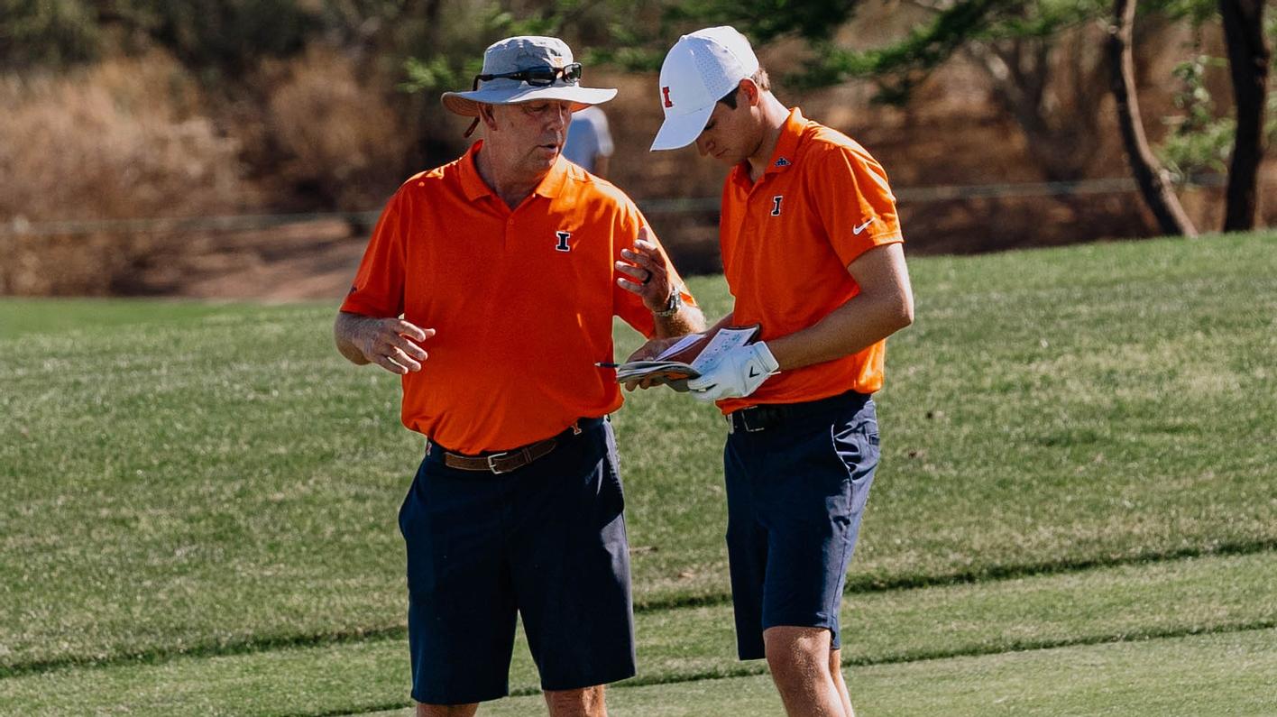 Men's Golf Coach Mike Small talks with a player on a green
