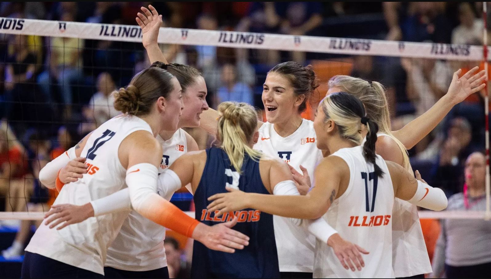 happy Illini volleyball players huddle on the court at Huff Hall