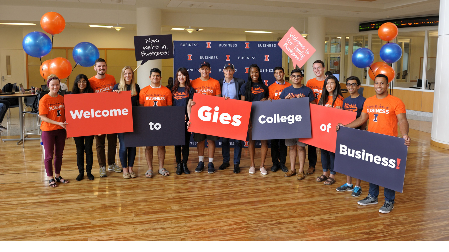 students hold placards announcing the new name of the college