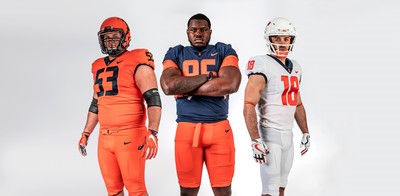 Three Illini football players wearing the new uniforms in blue, orange and white