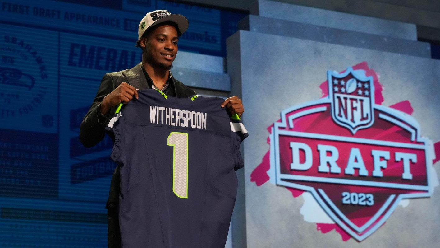 Devon Witherspoon holds up a Seattle Seahawks jersey bearing his name after being selected in the NFL draft