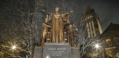 dramatic image of the Alma Mater statue and Algeld Chime Tower at night