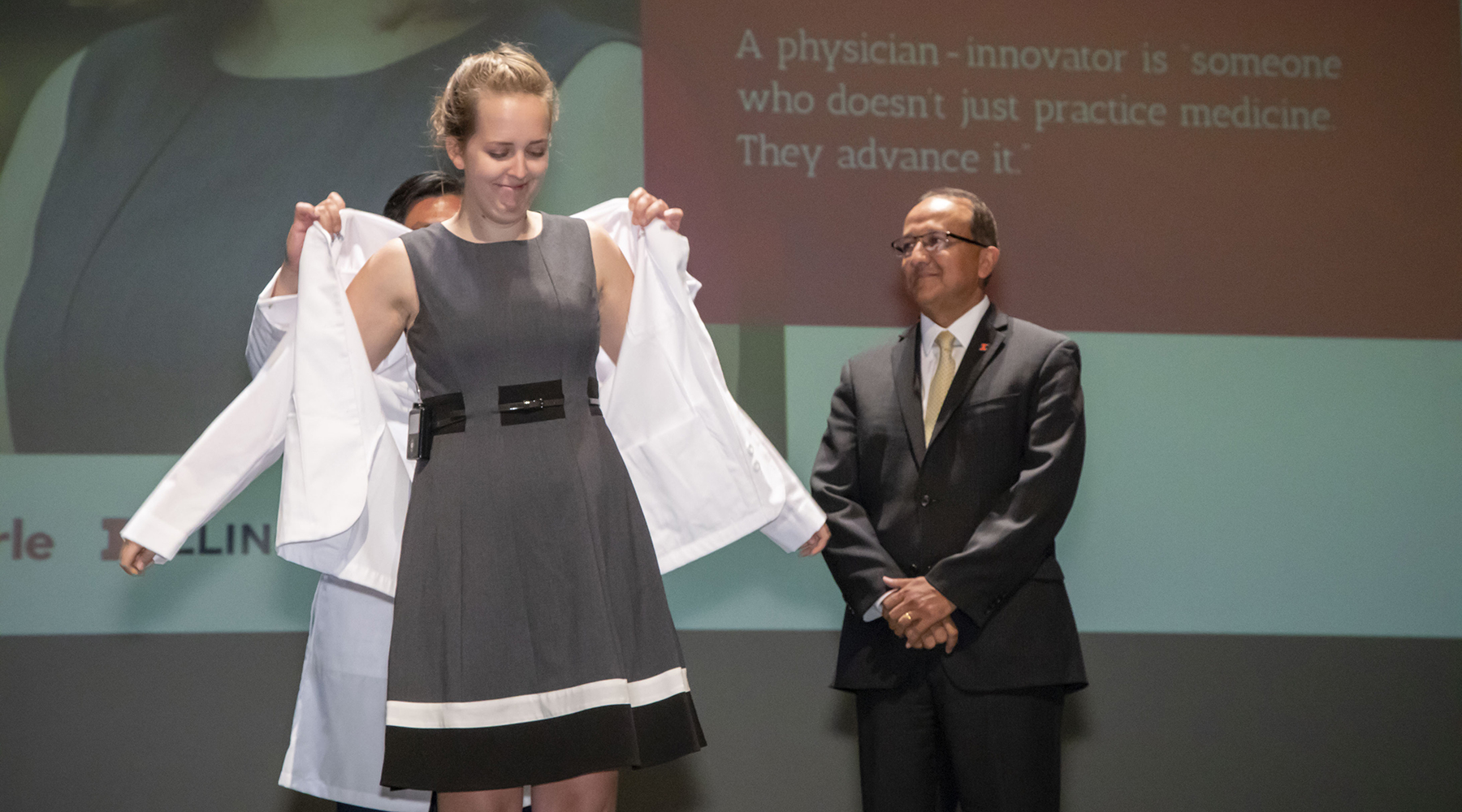 In a July ceremony, Elizabeth Woodburn receives her white coat, signifying that she is a physician-in-training, from dean King Li and executive associate dean Rashid Bashir. Photo by L. Brian Stauffer