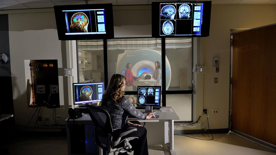 person monitors screens while patient enters an MRI machine
