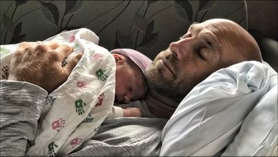 Josh Whitman reclines with baby on his chest