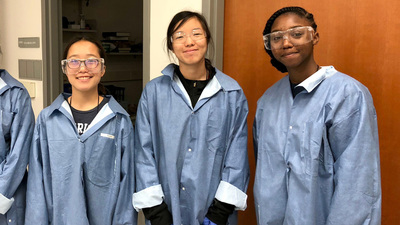 Participants in the 2018 Girls Learning Electrical Engineering (GLEE) camp wearing lab coats and googles.