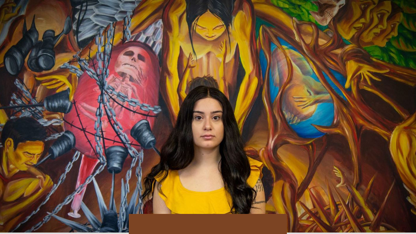 Carolina Kuhl in front of the murals from La Casa Cultural Latina